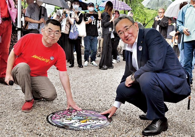 デザインマンホールに手を添える山下さんと石田市長